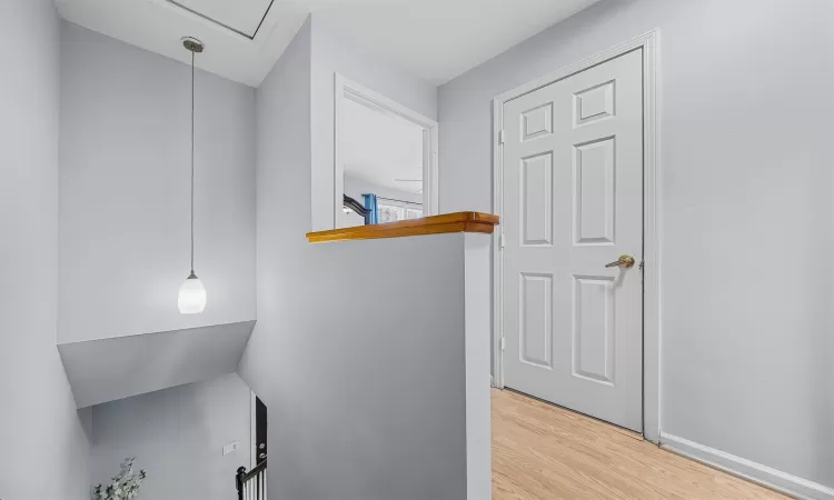 Corridor with attic access, baseboards, and wood finished floors