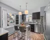 Kitchen with light wood finished floors, a baseboard radiator, stainless steel appliances, hanging light fixtures, and backsplash