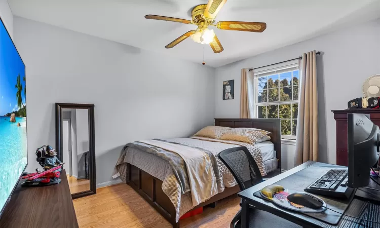 Bedroom featuring baseboards, light wood-type flooring, and ceiling fan