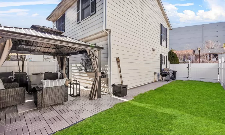 View of side of home with a gazebo, a patio, a lawn, and fence