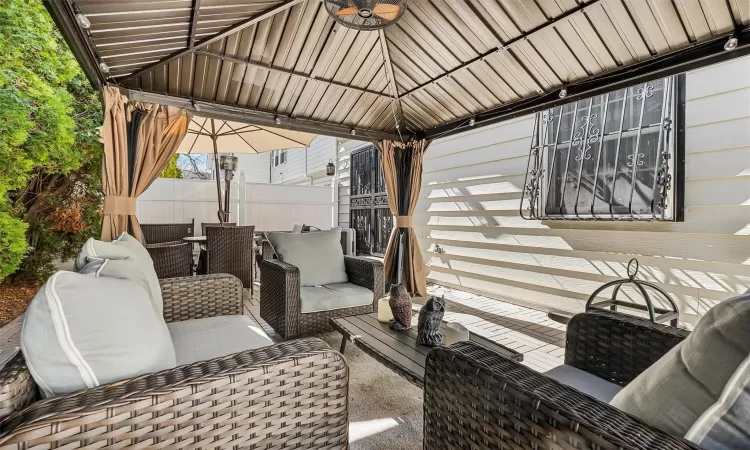 View of patio featuring ceiling fan, fence, a gazebo, outdoor lounge area, and outdoor dining space