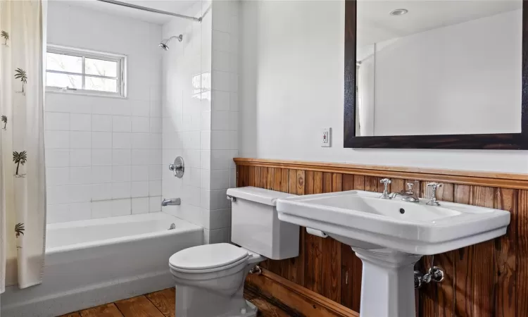 Bathroom with a sink, shower / bathtub combination with curtain, and toilet