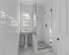 Bathroom with marble finish floor, a stall shower, and tile walls