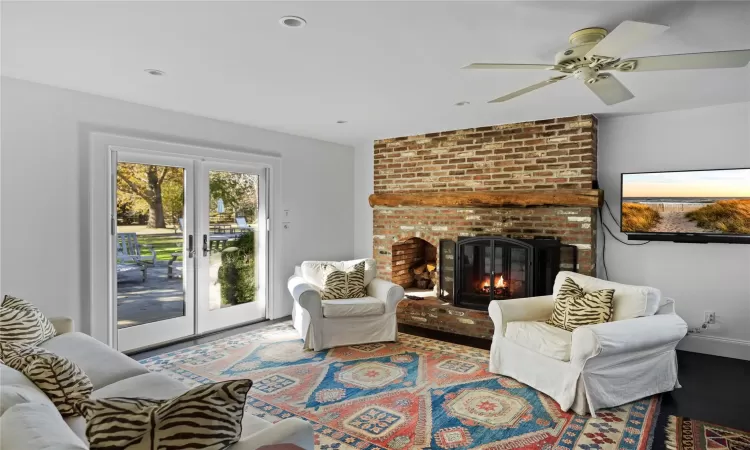 Living area featuring french doors, baseboards, a brick fireplace, and wood finished floors