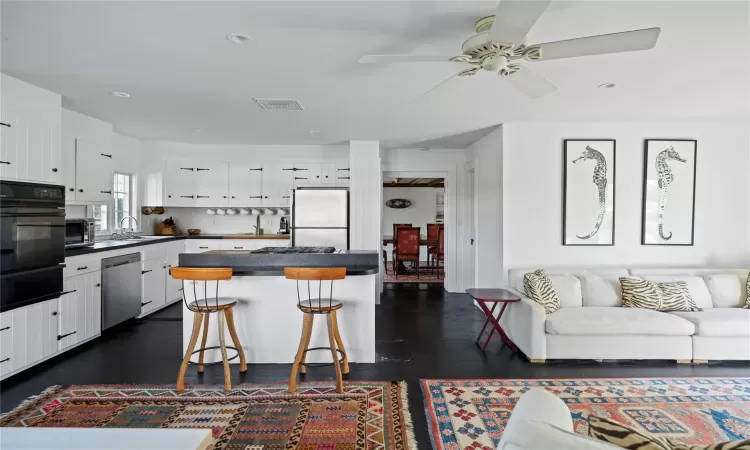 Kitchen with a warming drawer, freestanding refrigerator, stainless steel dishwasher, dark countertops, and black oven