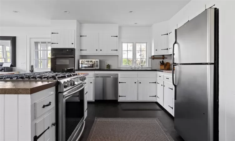 Kitchen featuring recessed lighting, a sink, white cabinets, appliances with stainless steel finishes, and dark countertops