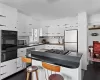 Kitchen featuring a warming drawer, a sink, dark countertops, appliances with stainless steel finishes, and white cabinets