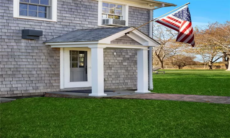 Entrance to property with a lawn and cooling unit