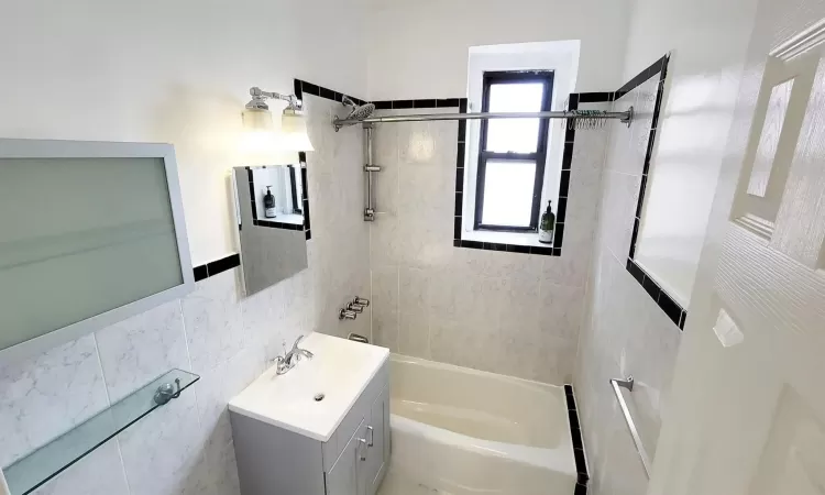 Full bathroom featuring tile walls, vanity, and bathtub / shower combination