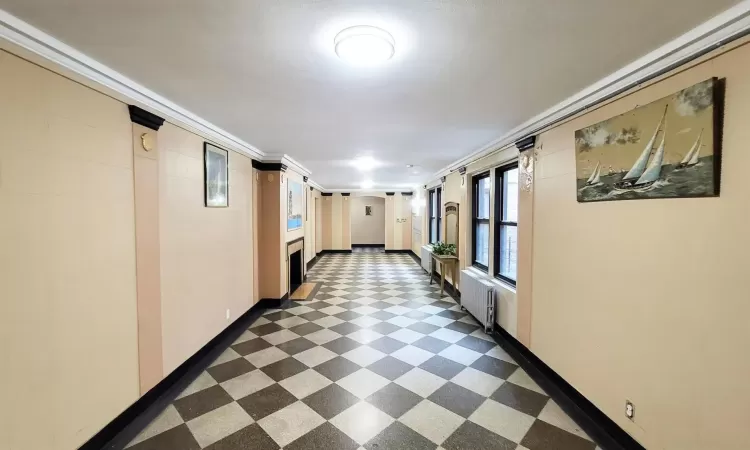 Corridor with crown molding, radiator, dark floors, and baseboards