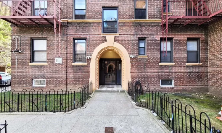 View of exterior entry featuring brick siding and fence