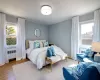 Bedroom featuring multiple windows, radiator heating unit, and wood finished floors