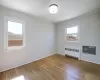 Unfurnished room featuring a wall mounted air conditioner, ornamental molding, hardwood / wood-style flooring, radiator, and baseboards