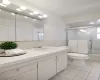 Bathroom with vanity, enclosed tub / shower combo, tile patterned flooring, tile walls, and toilet