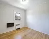 Empty room with heating unit, crown molding, radiator, and wood-type flooring