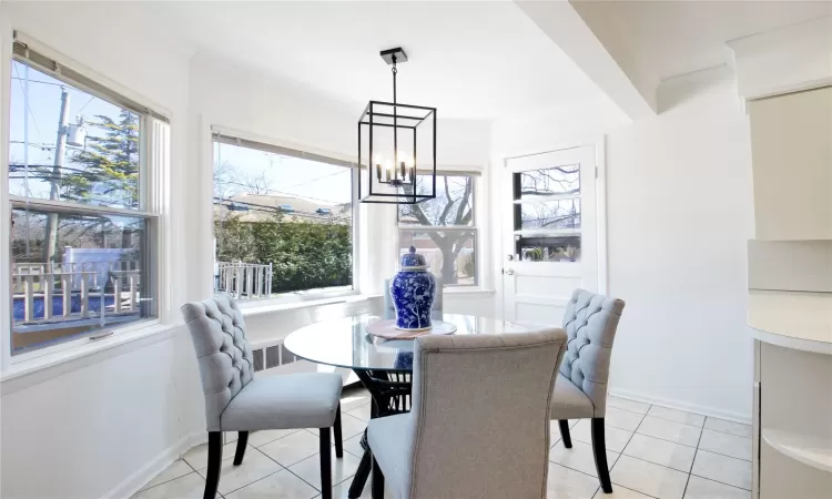 Dining area with light tile patterned floors, a chandelier, crown molding, and baseboards