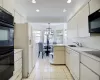 Kitchen with light tile patterned floors, a sink, black appliances, light countertops, and crown molding