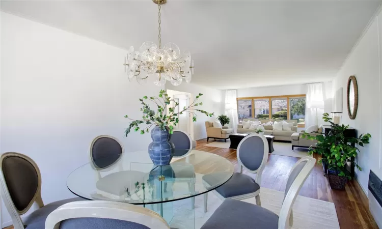 Dining room featuring a chandelier, crown molding, baseboards, and wood finished floors