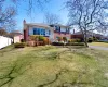 Split level home with a front lawn, brick siding, a chimney, and fence