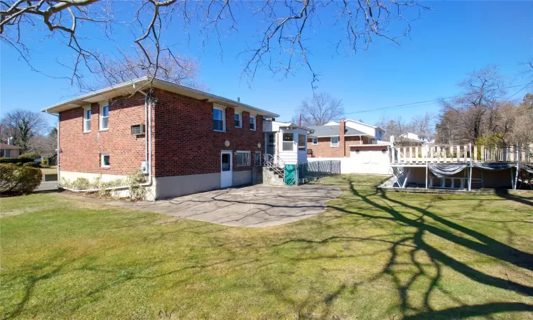 Back of property with brick siding, a pool, a patio area, and a yard