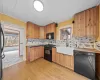 Kitchen featuring black appliances, a sink, tasteful backsplash, light wood finished floors, and wood ceiling