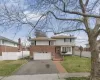 Tri-level home featuring aphalt driveway, an attached garage, fence, and a front lawn