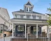 View of front of house with a fenced front yard, a balcony, a porch, and roof with shingles