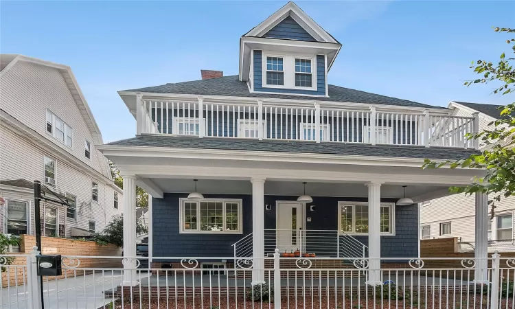 View of front of house with a fenced front yard, a balcony, a porch, and roof with shingles