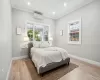 Bedroom with light wood-type flooring, baseboards, and an AC wall unit