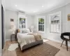 Bedroom featuring multiple windows, light wood-style floors, crown molding, and a wall mounted AC