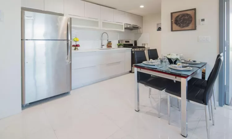 Kitchen featuring under cabinet range hood, appliances with stainless steel finishes, modern cabinets, and a sink