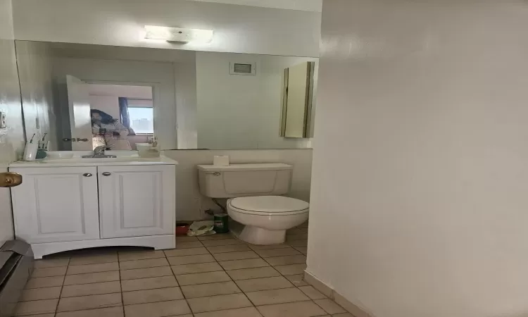 Half bathroom featuring tile patterned floors, visible vents, toilet, and vanity