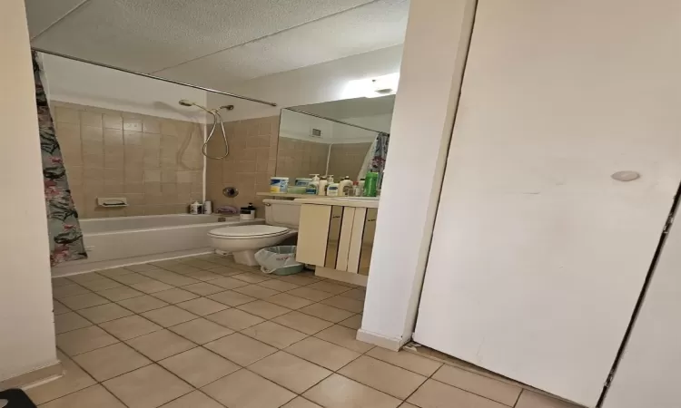 Full bath with tile patterned floors, shower / tub combo with curtain, toilet, a textured ceiling, and vanity