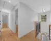 Corridor with an upstairs landing, baseboards, attic access, and light wood-style floors