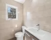 Full bathroom with double wide shower, toilet, tile walls, and vanity