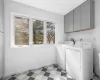 Clothes washing area with cabinet space, washer and dryer, light floors, and baseboards