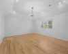 Unfurnished room with light wood finished floors, visible vents, baseboards, lofted ceiling, and a notable chandelier