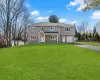 View of front of property with a front lawn, driveway, stone siding, fence, and an attached garage