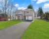 View of front of house with driveway, a front lawn, a garage, and fence