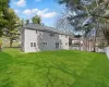 Back of property featuring a yard, a shingled roof, and fence