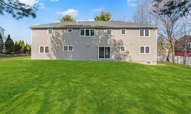 Back of house with a yard and fence