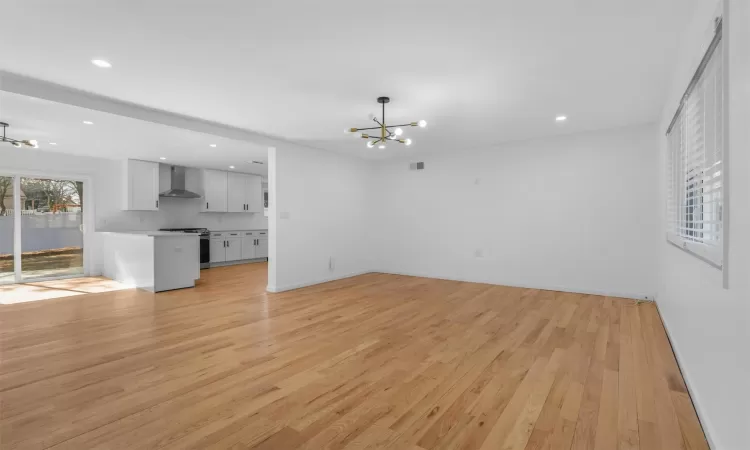 Unfurnished living room with recessed lighting, baseboards, light wood finished floors, and a chandelier