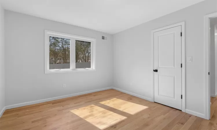 Unfurnished room featuring light wood finished floors, visible vents, and baseboards