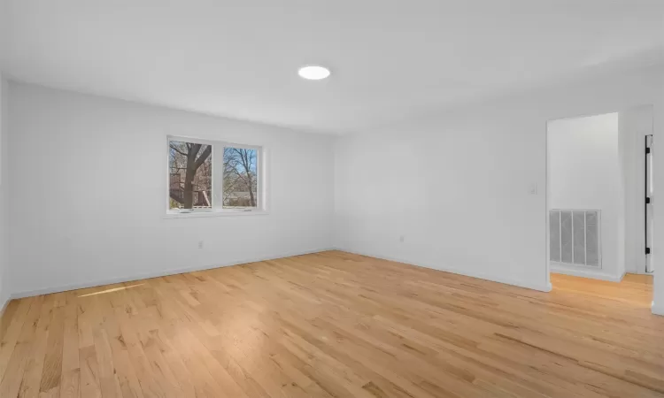 Empty room featuring light wood-style floors, visible vents, and baseboards