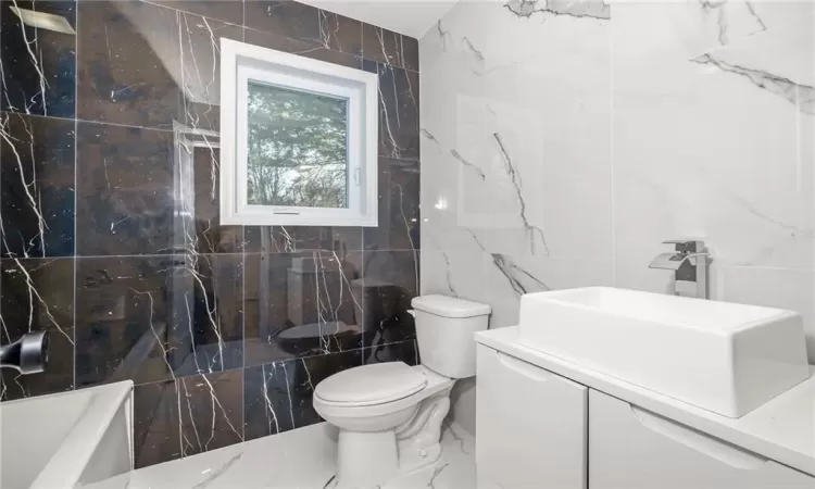 Bathroom with vanity, bathing tub / shower combination, tile walls, toilet, and marble finish floor