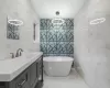 Bathroom with a freestanding tub, marble finish floor, tile walls, and vanity