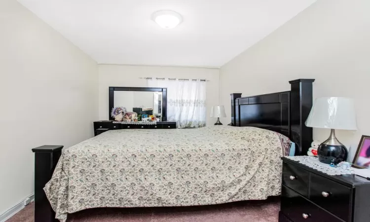 Bedroom featuring baseboards and dark carpet