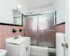 Bathroom with shower / bath combination with glass door, tile walls, vanity, and toilet