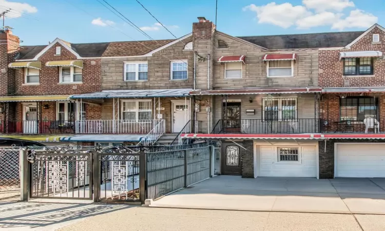 View of property with a fenced front yard, stone siding, an attached garage, and driveway