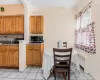 Kitchen featuring brown cabinetry, stainless steel microwave, radiator heating unit, and a sink